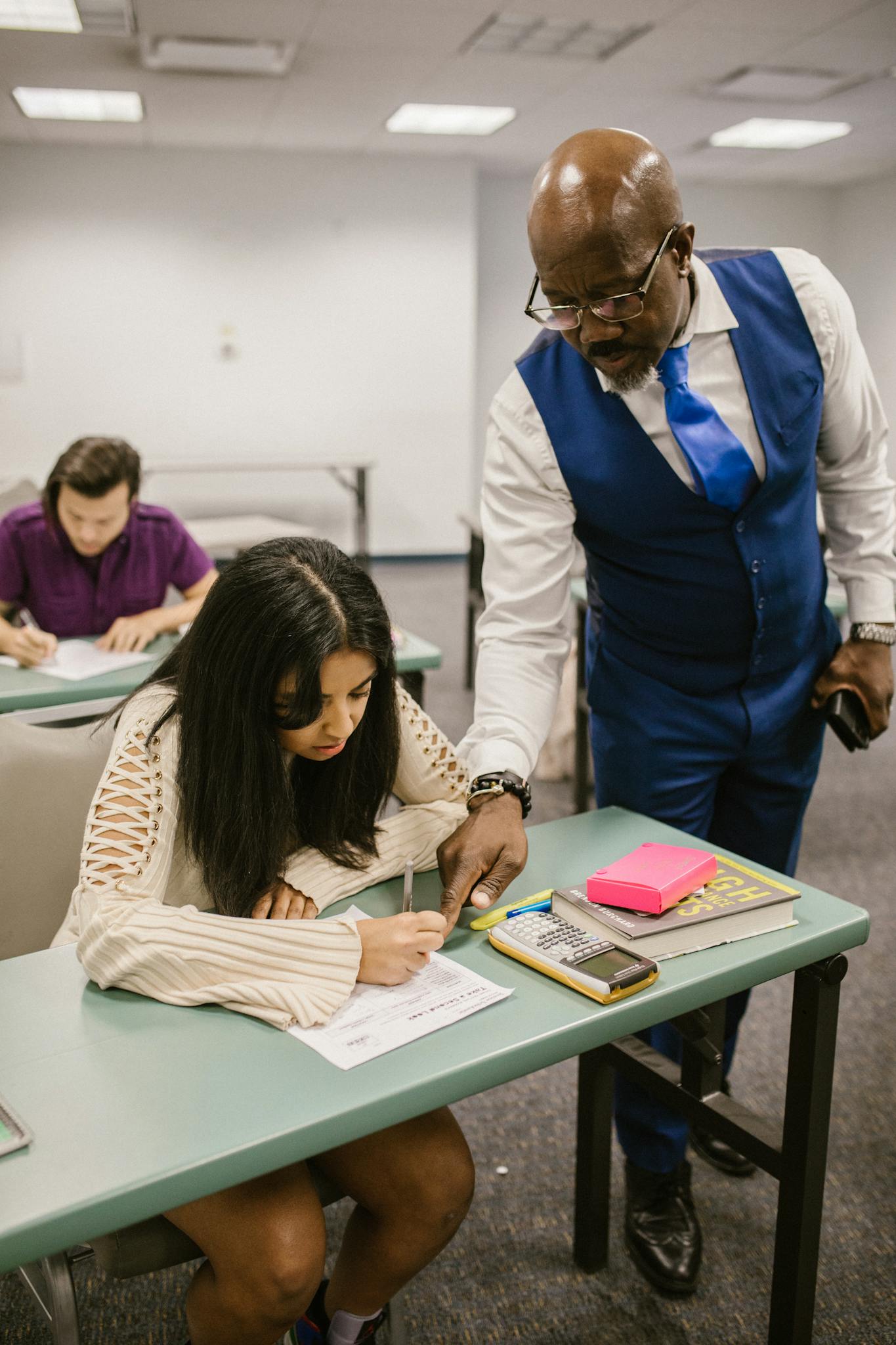 Educator Assisting Student During An Exam In